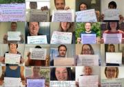 People holding up posters with their messages of support for the independent visitor campaign