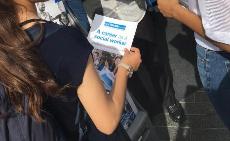 A girl holding a 'Career in social work' leaflet